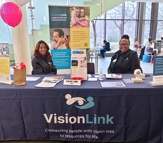 Alexis Morrison, Vision Link’s Vision Rehabilitation Therapist, and Sylvia Purnell, Director of Community Engagement and Partnerships, seated at a table at a community outreach event.